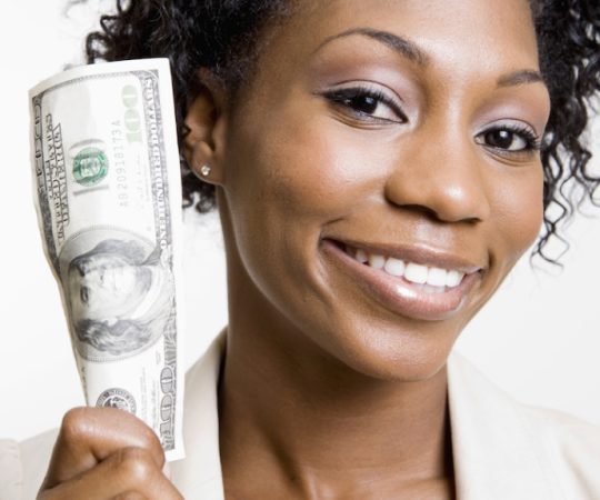 African American woman holding hundred dollar bill